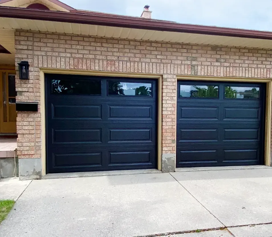 Two black raised-panel garage doors installed on a brick bungalow in White Oaks, London